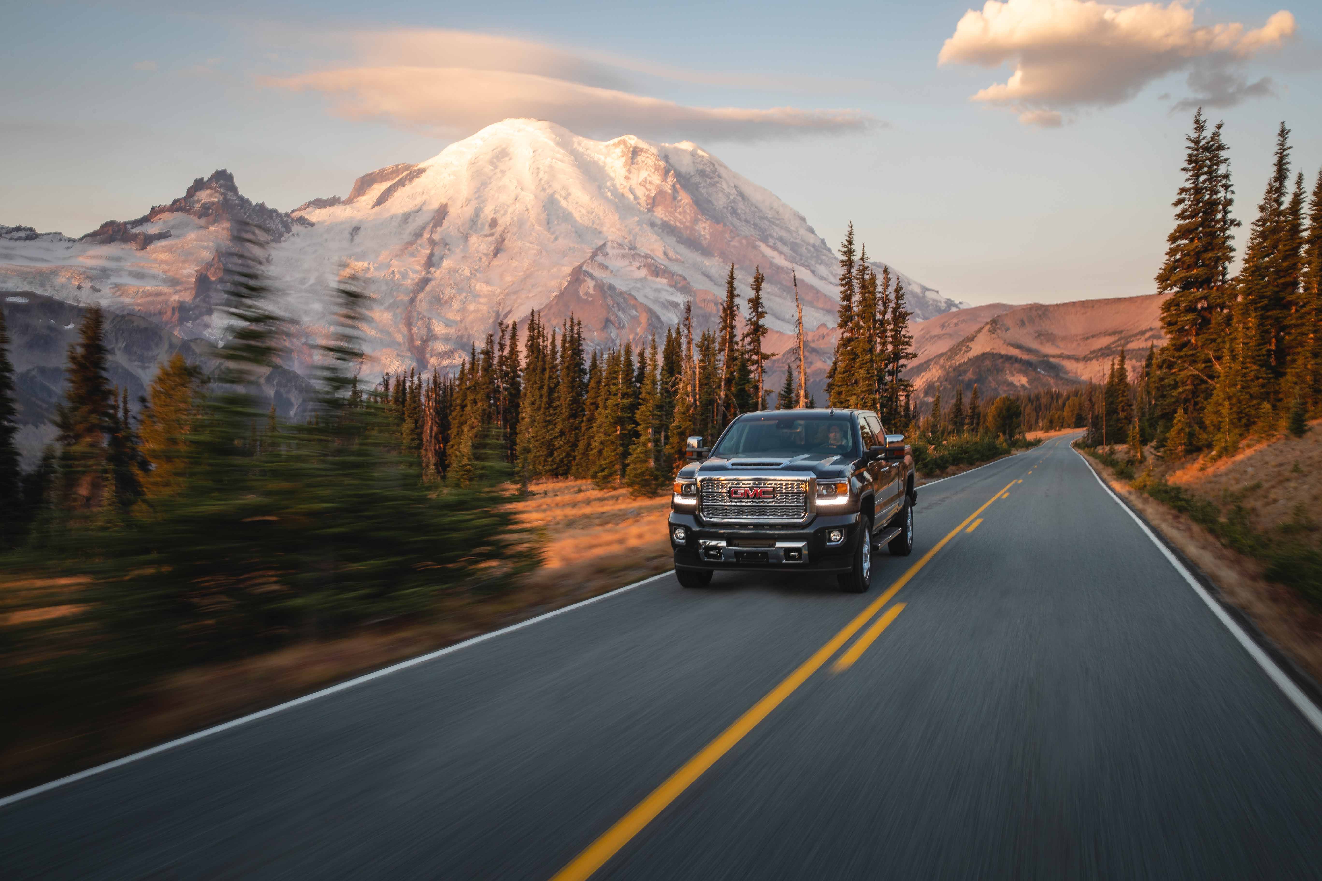 Outdoor photography of a GMC Truck driving on Mount Rainier during sunrise