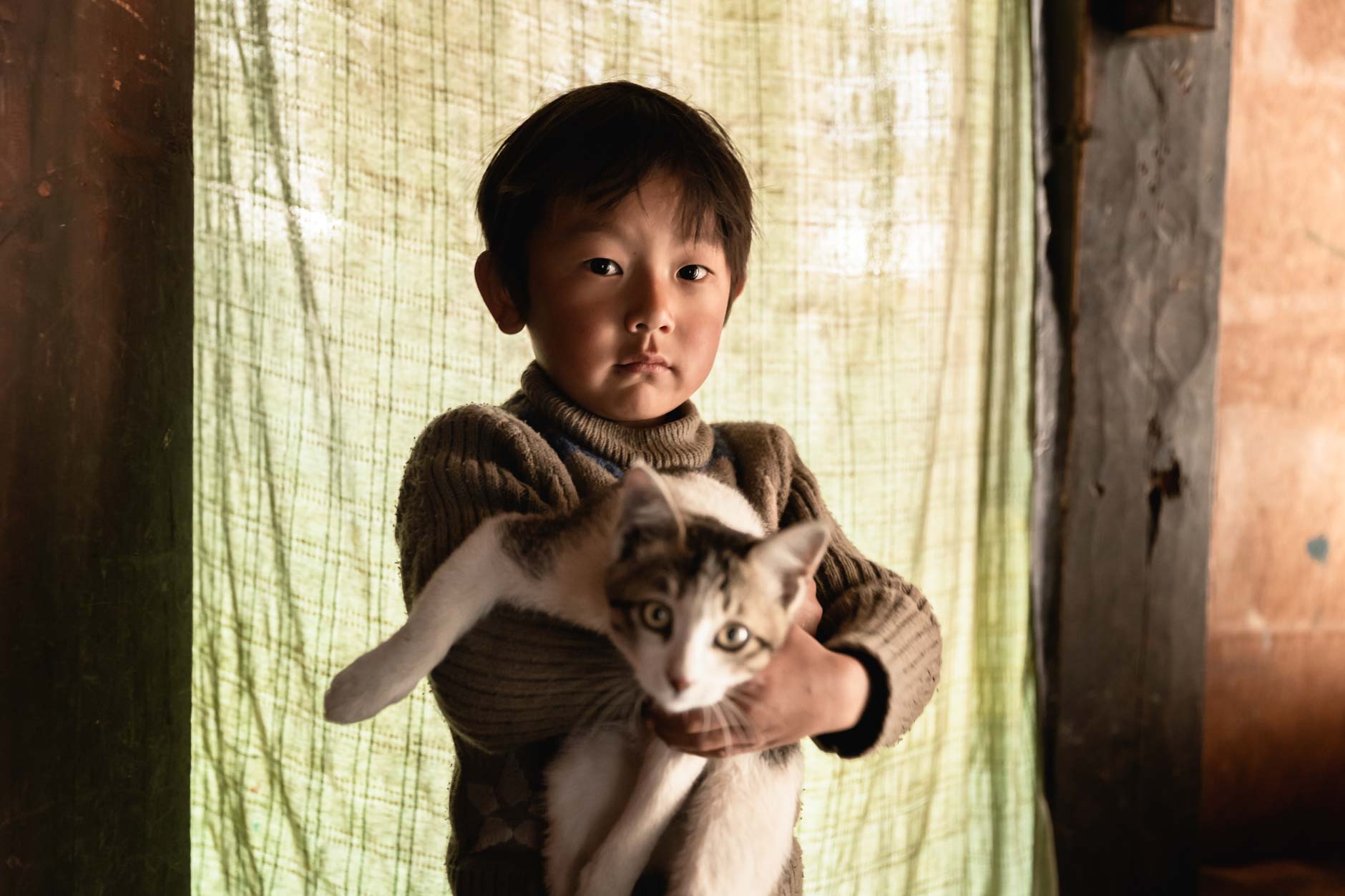 Portrait photography of a young Bhutanese boy holding a cat