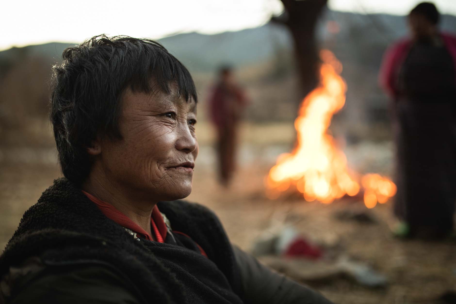Portrait photography of an elderly Bhutanese woman next to a fire