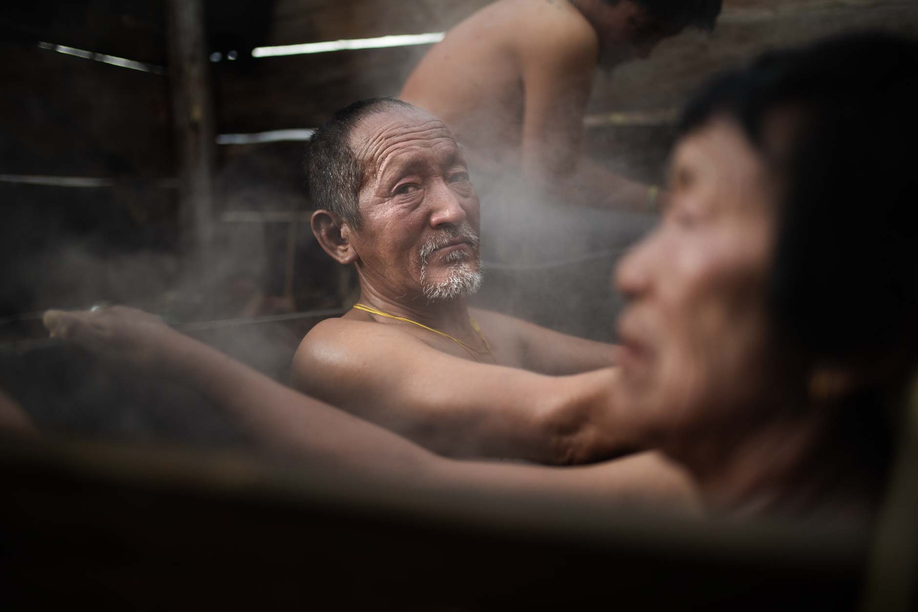 Portrait photography of an elderly Bhutanese man taking a traditional hot stone bath in a village in Bhutan