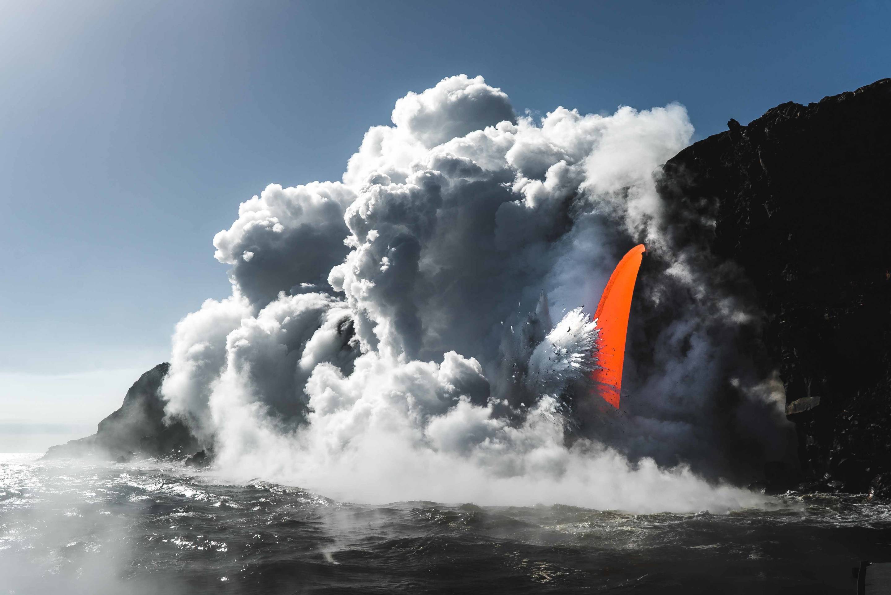 A fire hose lava spout in Hawaii Volcanoes National Park viewed from a boat