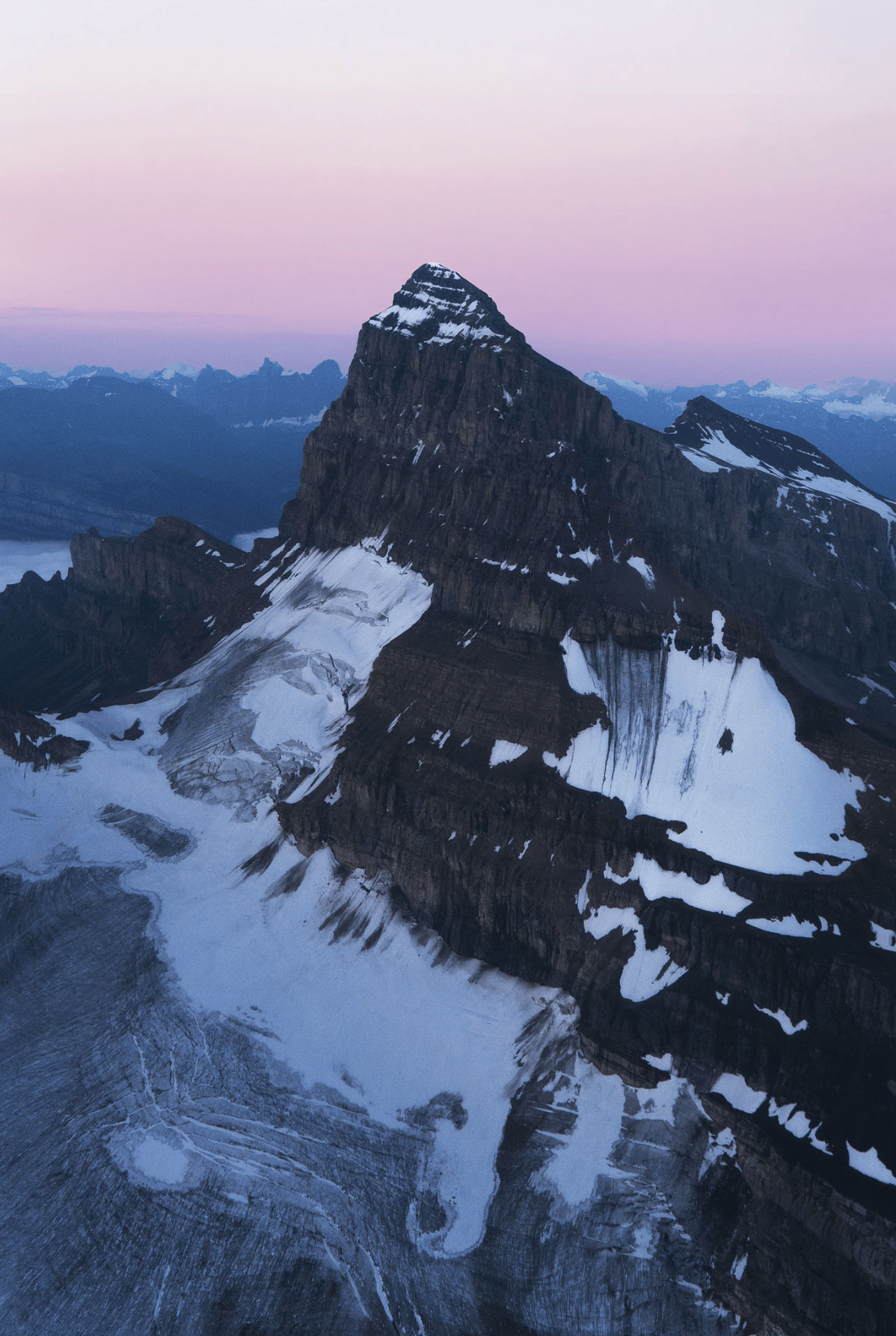 Aerial photography from a helicopter of mount chephren in Banff National Park during sunrise above the fog Photo by Andrew Studer