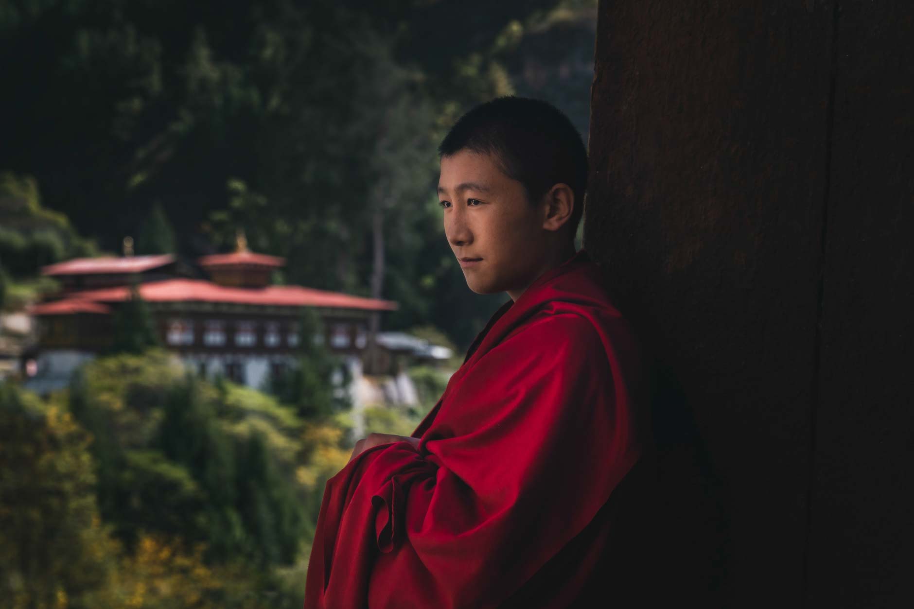 Portrait photography of a young Bhutanese monk wearing red robes in Paro Dzong