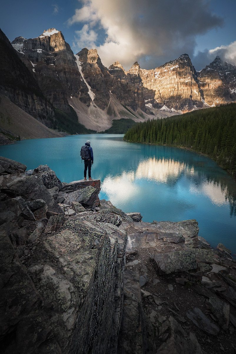 A person stands on a rock at Moraine Lake in Banff National Park in the Canadian Rockies