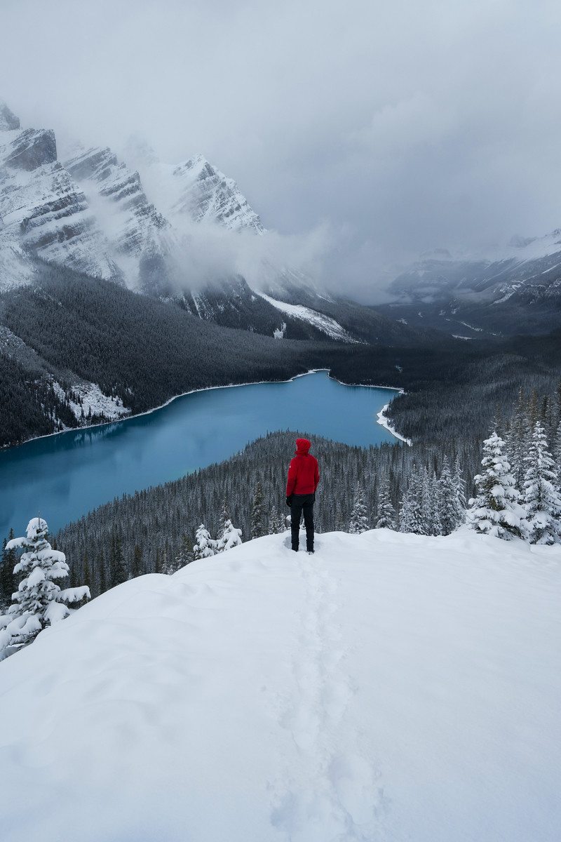 A person in a red jacket standing at a snowy Peyto Lake in the Canadian Rockies in Banff National Park