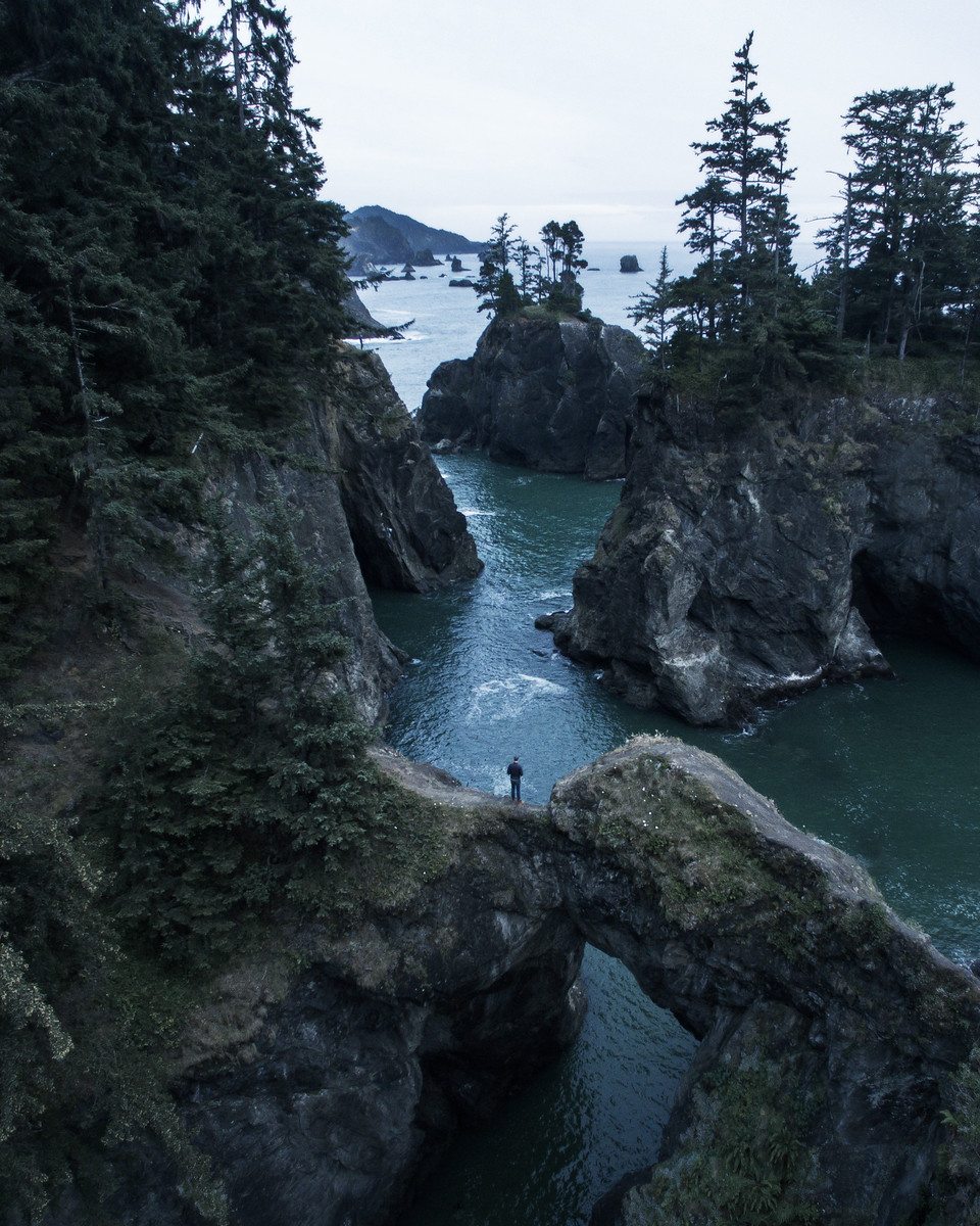 A person stands on an arch at Samuel H Boardman State Park on the Oregon Coast