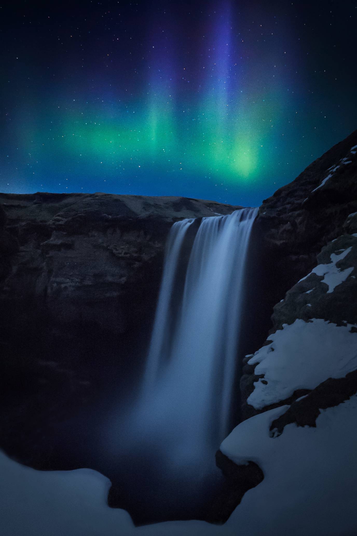 Night photography of the northern lights over Skogafoss Waterfall, Iceland