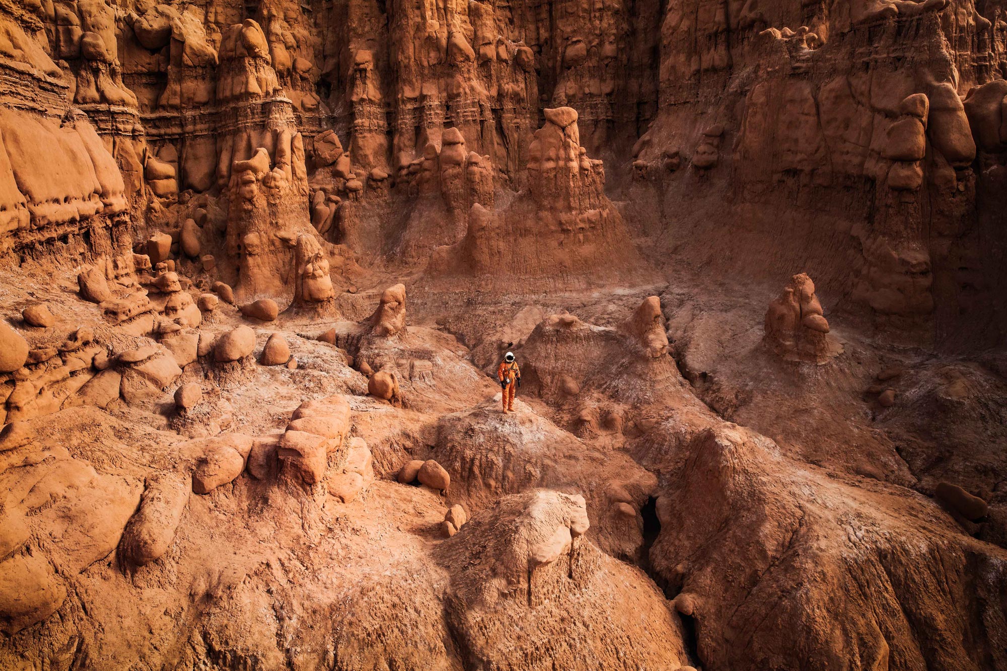 An astronaut walks through the otherworldly landscape of the Arizona desert.
