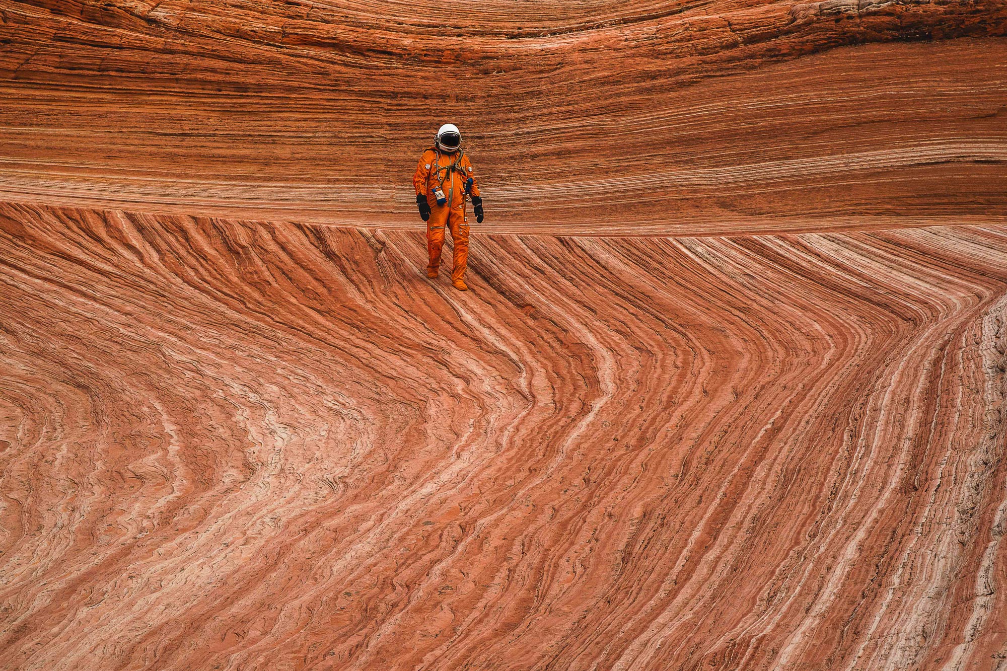 An astronaut walking on the mars-like landscape of the desert in the American Southwest