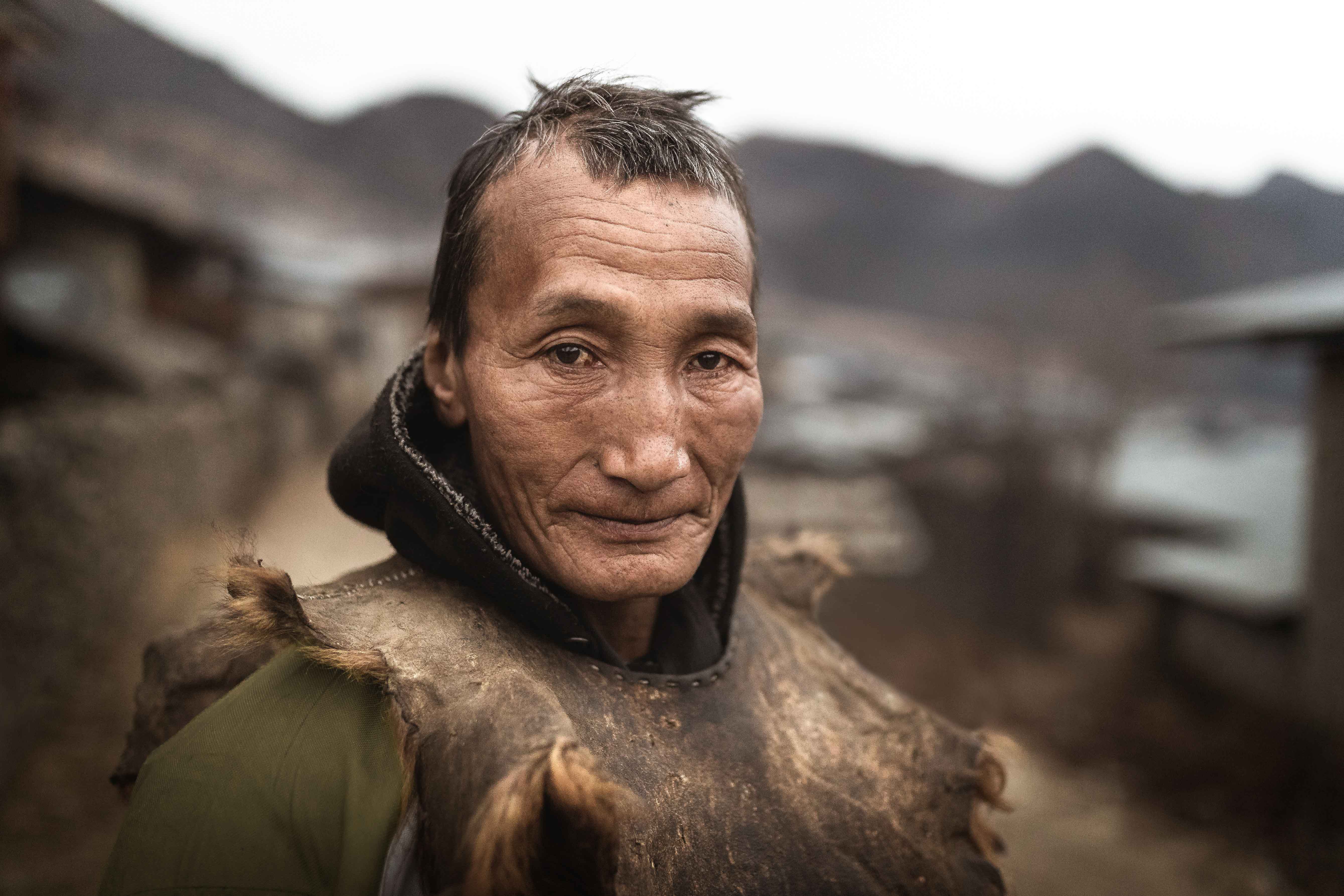 Photography of a brokpa tribesman wearing a leather yak vest in Merak, Bhutan