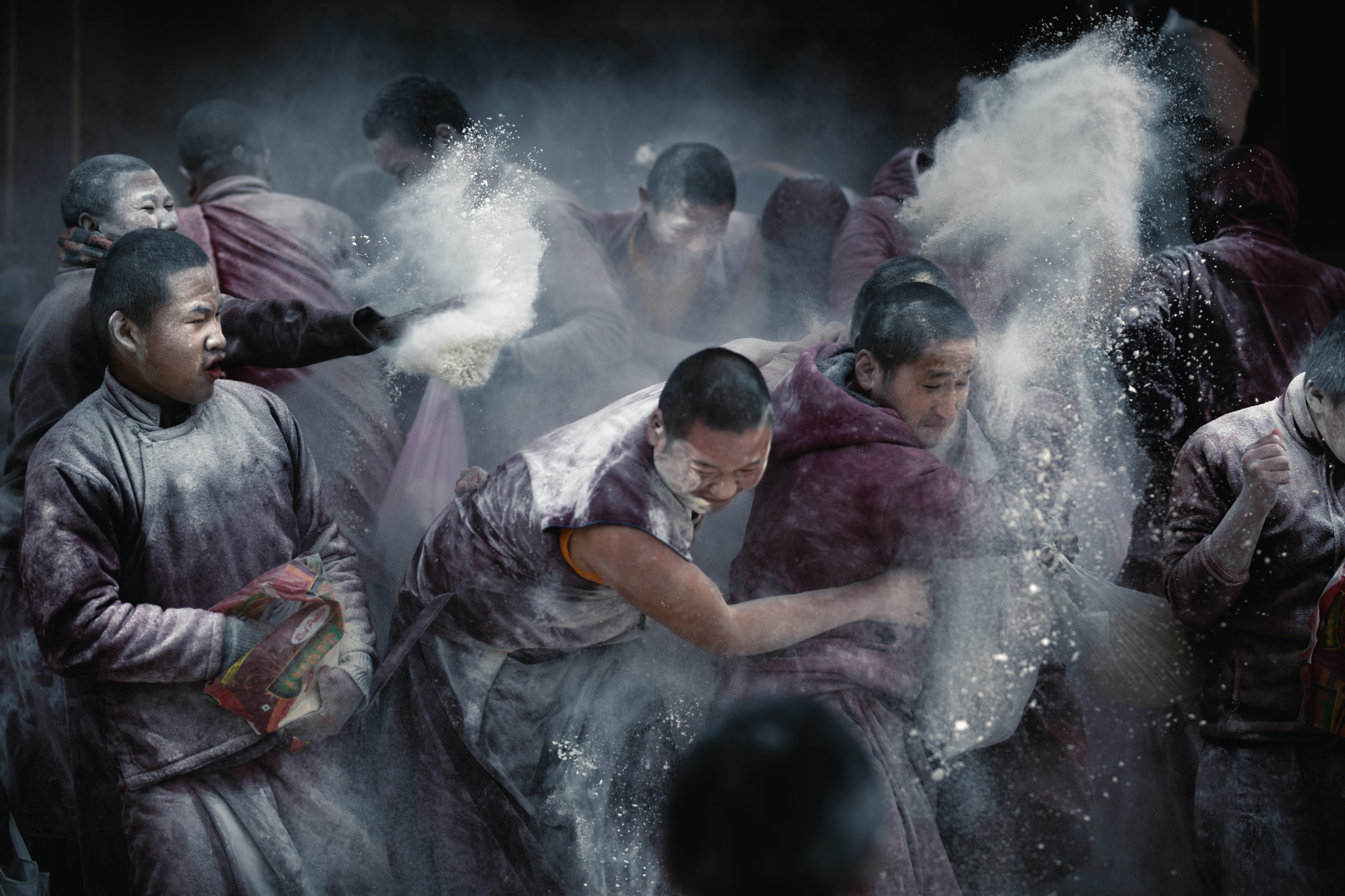 Photography of young Buddhist monks celebrating the Bhutanese New Year (Losar festival) by throwing powder and flour at each other at a monastery in Bumthang