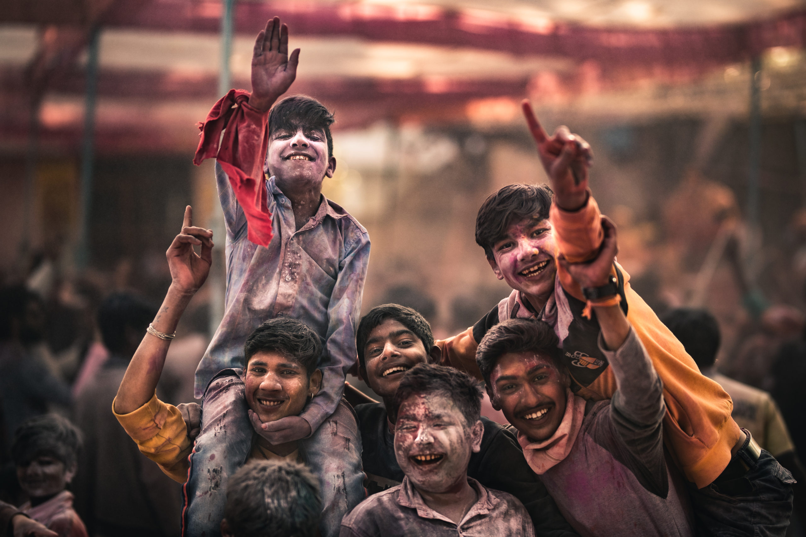 Street photography of children dancing and celebrating the holi festival while covered in colorful powder during the holi festival of colors in Mathura, India