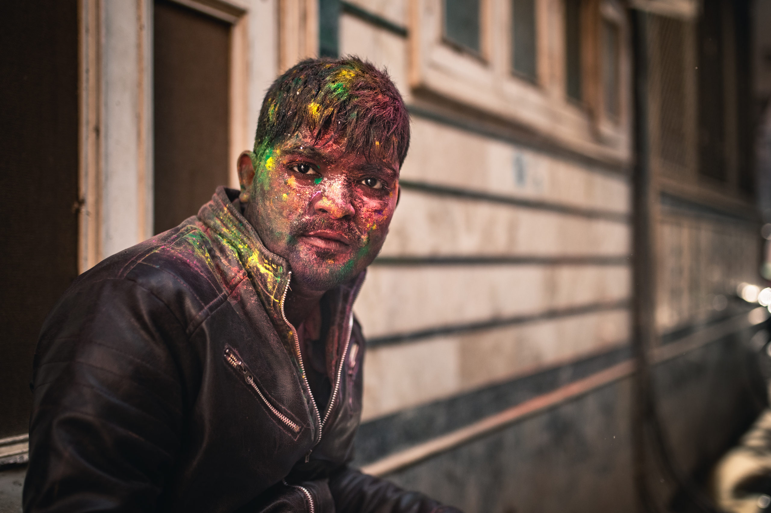 Portrait photography of a man with colorful holi powder covering his face in the streets of Vrindivan, India during the Holi Festival of Colors 2020