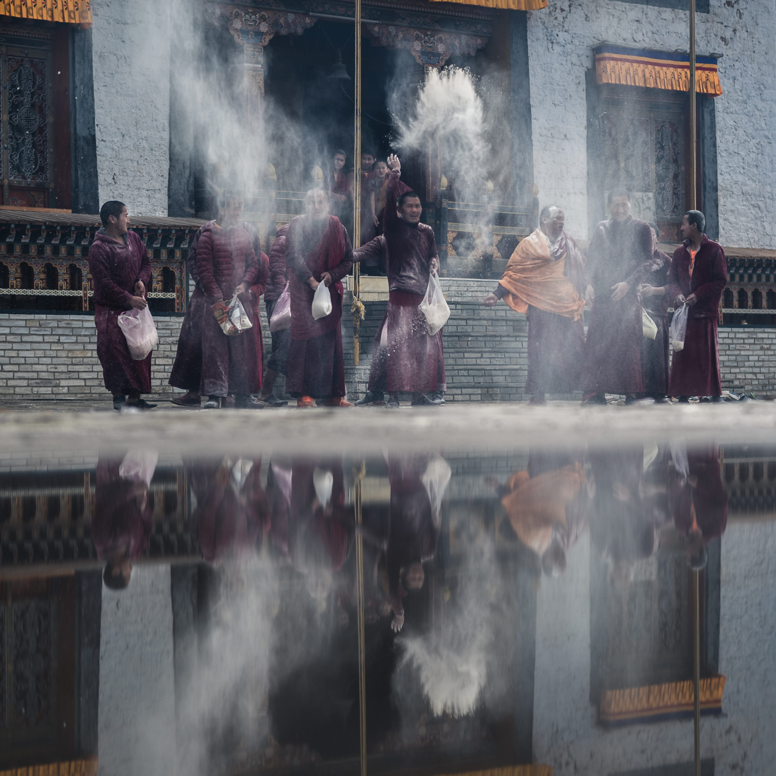 A group of Buddhist monks throwing flour into the air during the New Year celebration at a temple in Bhutan