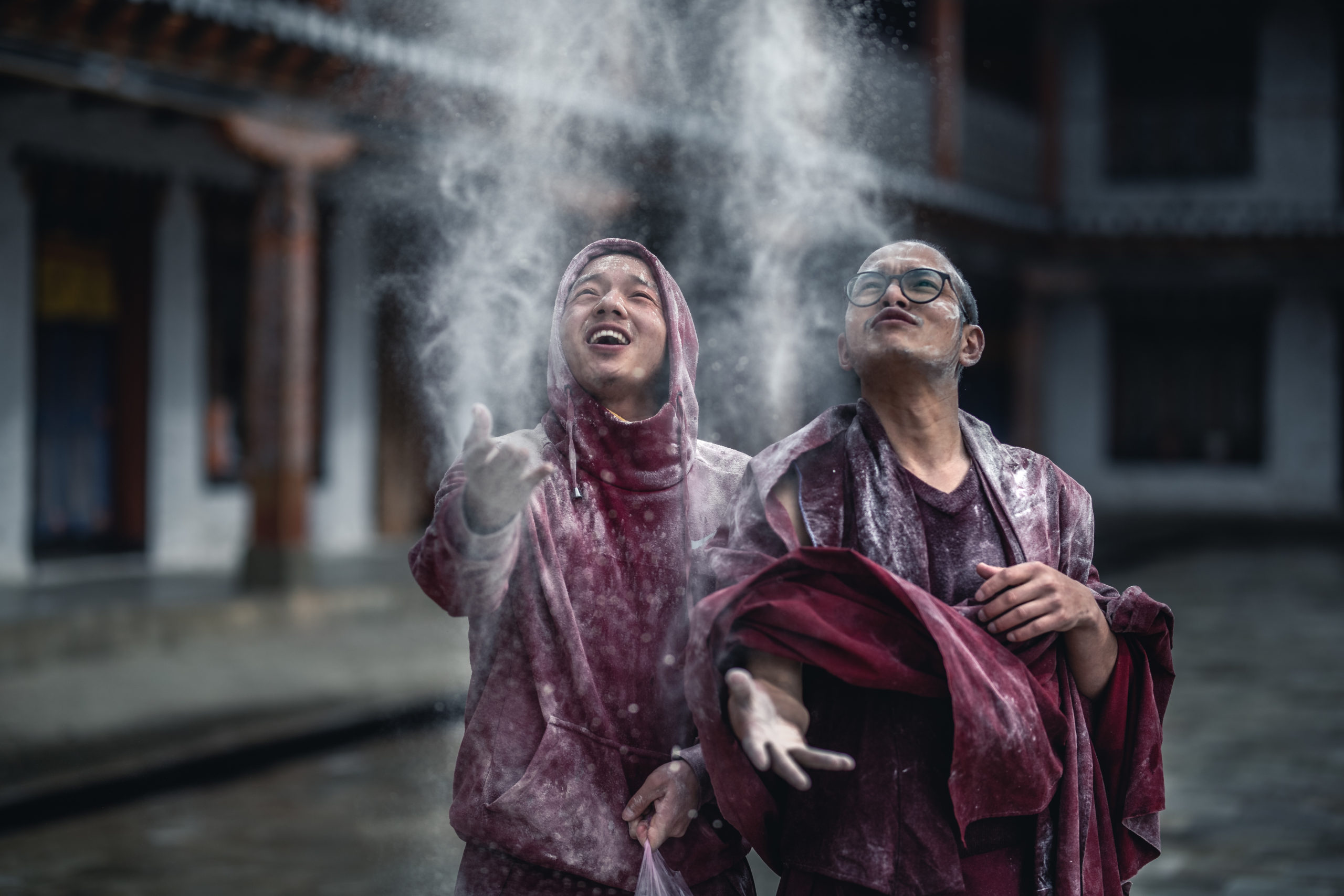 Portrait photography of two Buddhist monks throwing flour into the air during the Losar Celebration in Bhutan