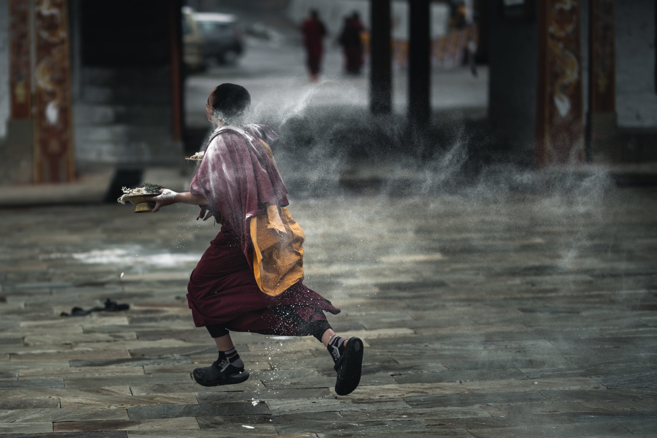Photography of young Buddhist monks celebrating the Bhutanese New Year (Losar festival) by throwing powder and flour at each other at a monastery in Bumthang