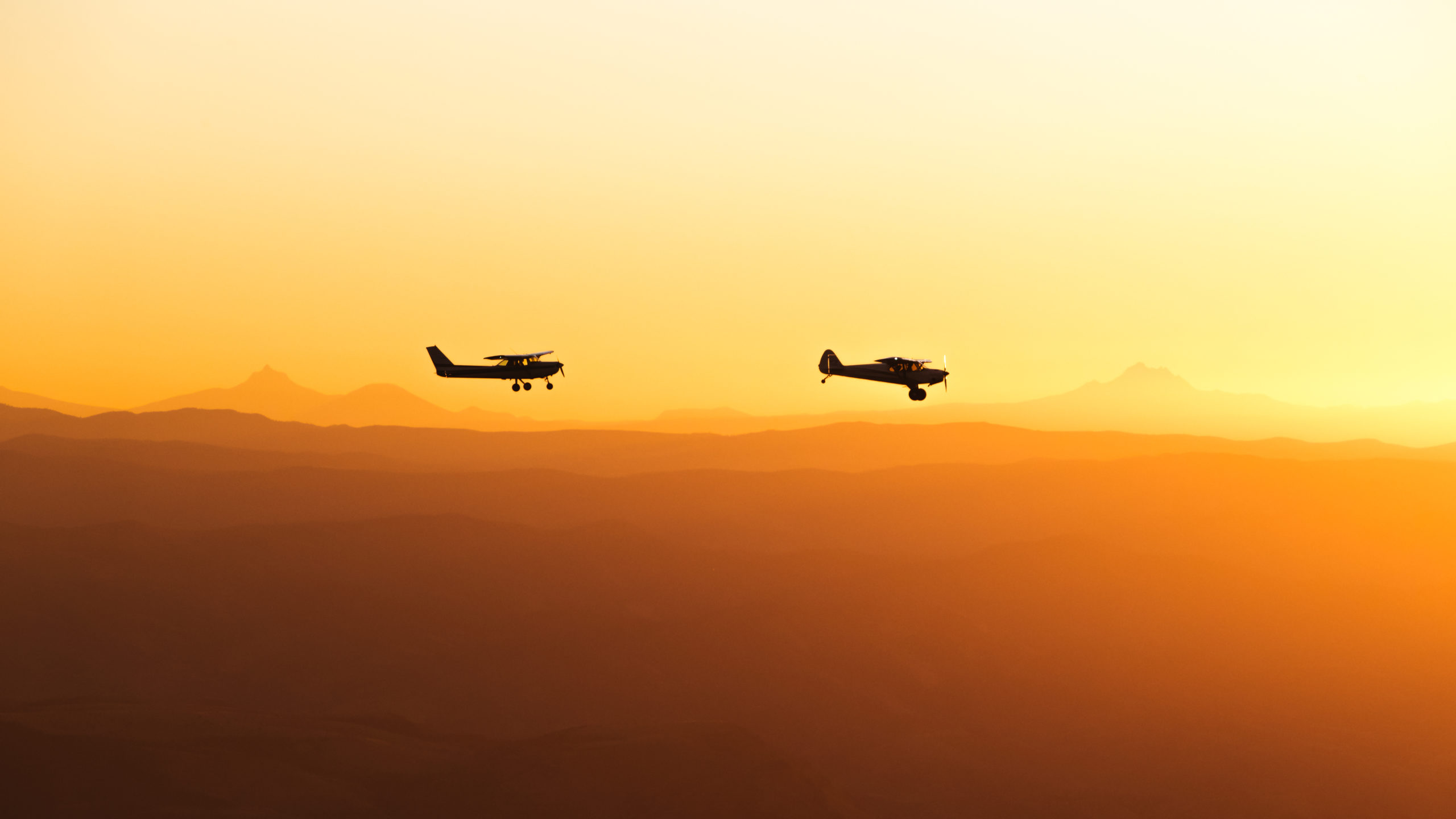 Aviation Photography of two airplanes flying over mountains in Oregon during Sunset