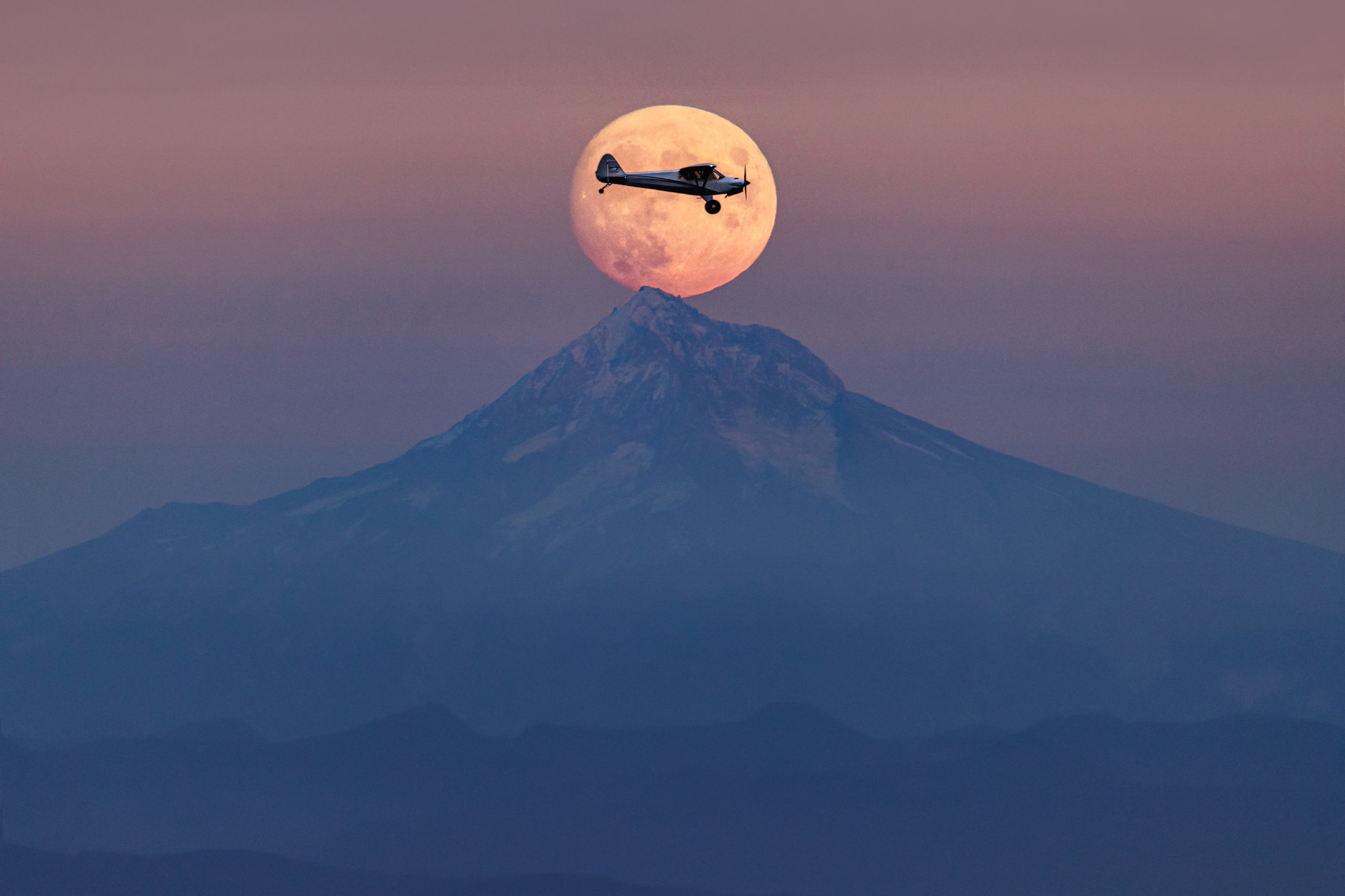 Aviation landscape photography of an airplane within the rising full moon over Mount Hood, Oregon. Single image, no photoshop.