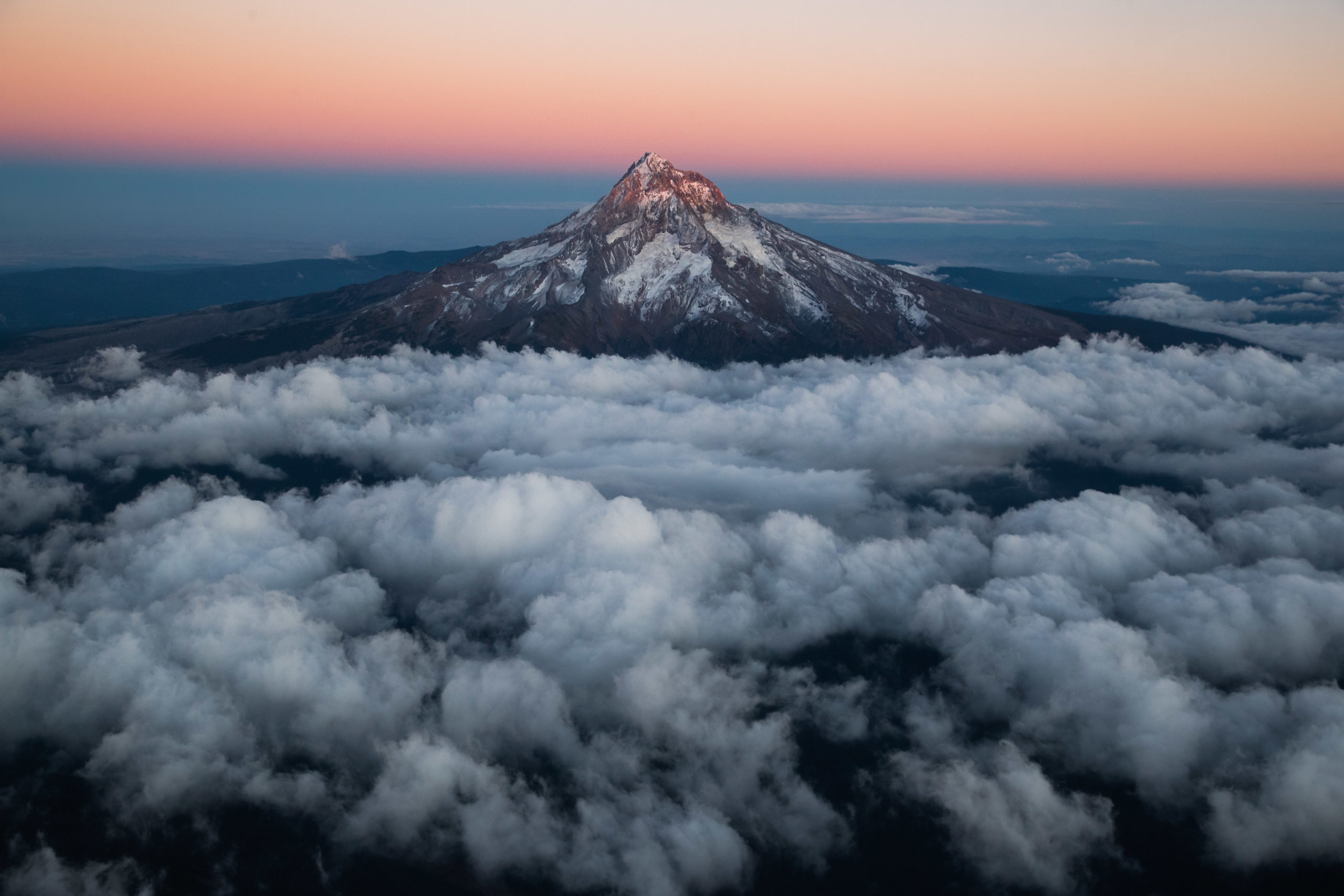 Aerial landscape photography of Mount Hood, Oregon rising high above the clouds taken during sunset