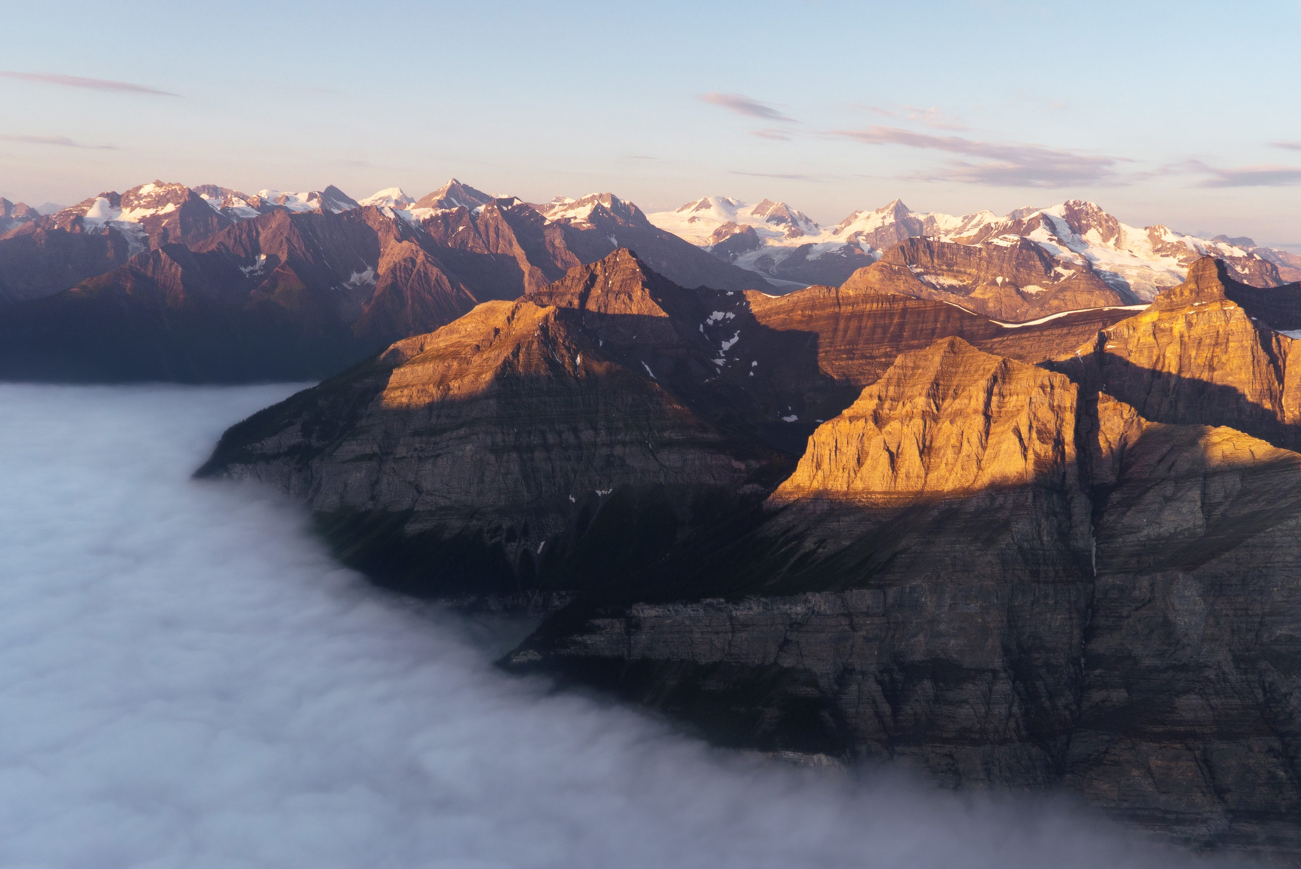 Aerial photography taken from a helicopter of mountains above the fog in Banff National Park, Canada