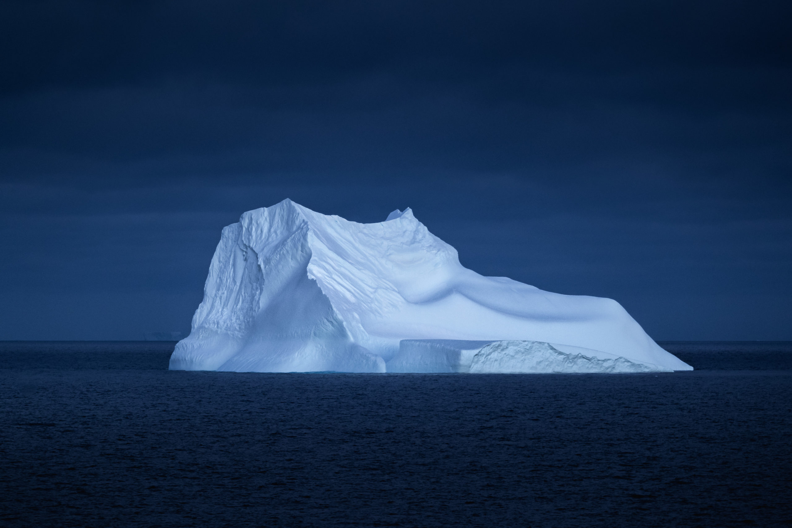 Landscape photography of a large Iceberg floating in the Antarctic sea at night