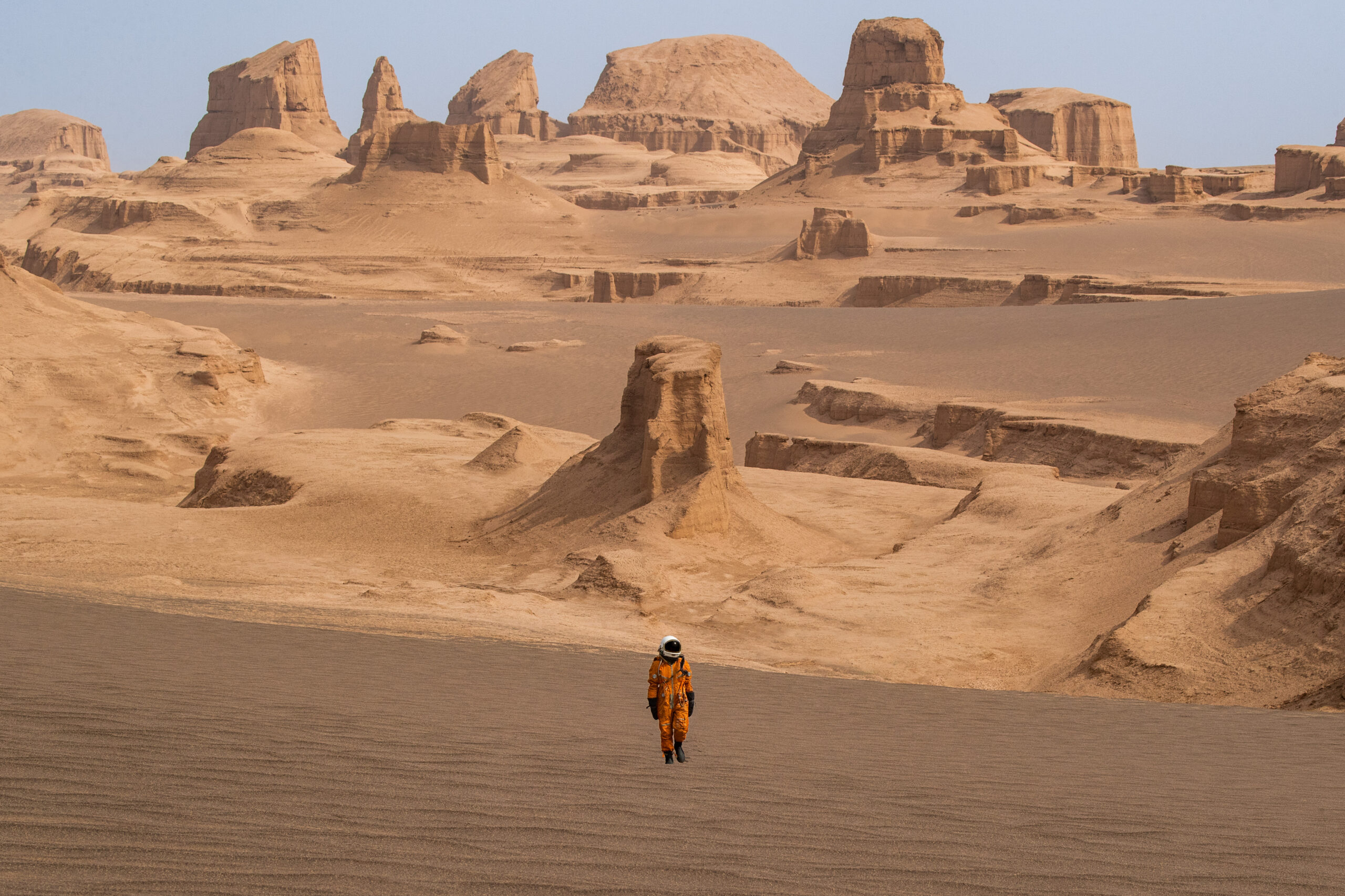Photography of an astronaut walking through Iran's Dasht-e Lut desert in Central Iran