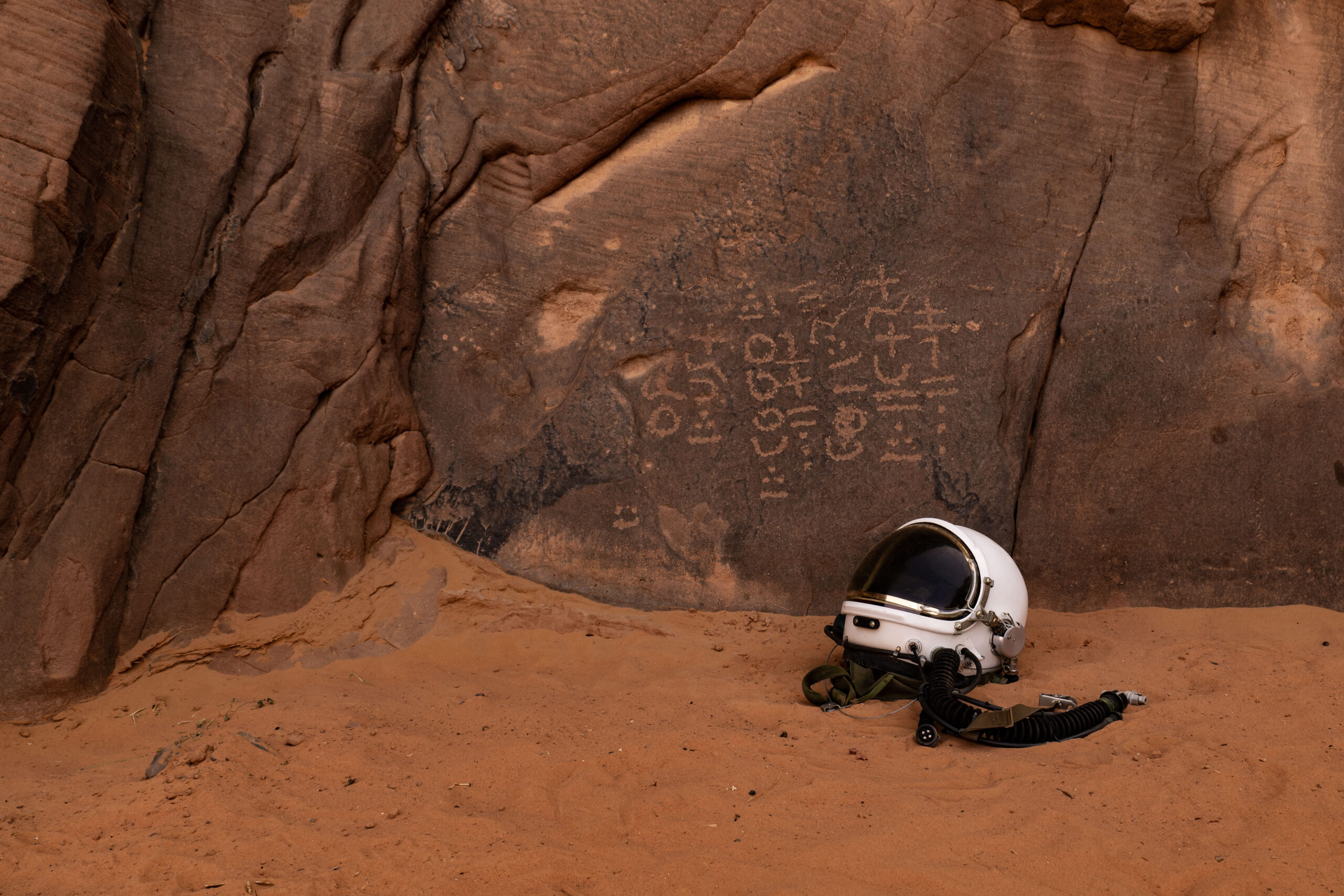 Astronaut helmet from 'Space to Roam' laying next to ancient engravings from over 3,000 years ago in Algeria