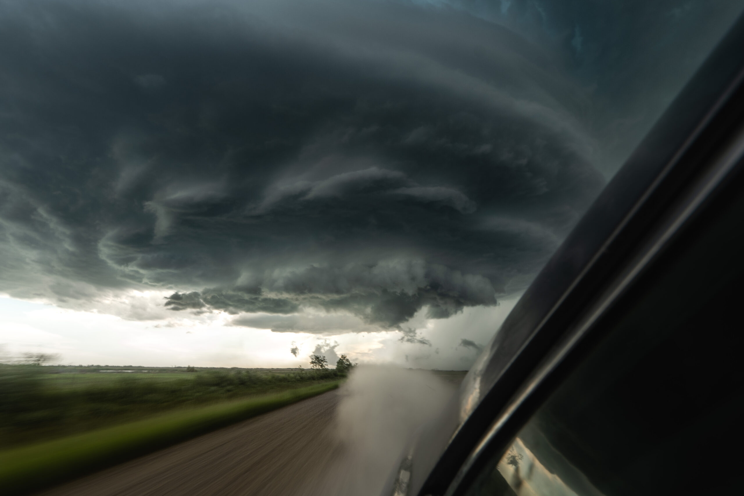 Quickly driving to get in position to capture a large supercell storm in Canada with storm chaser Tanner Charles