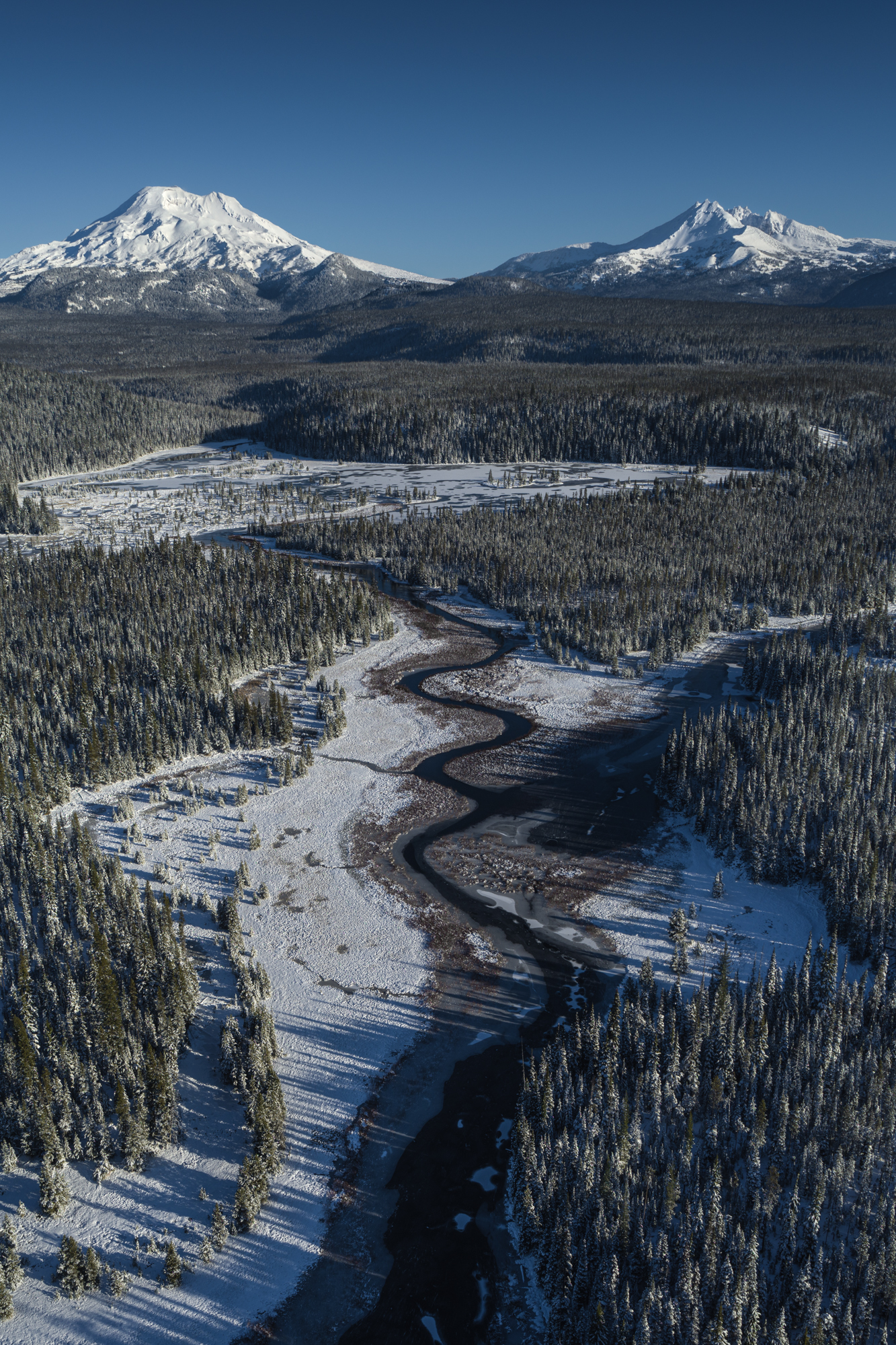 Aerial landscape photography of a beautiful 'S curve' stream with Oregon's iconic South Sister and Broken Top Mountain in the distance