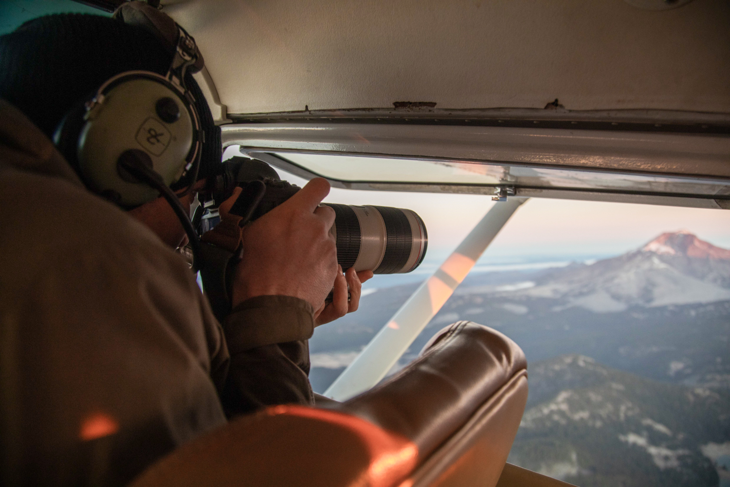 Behind the scenes of aerial photographer Andrew Studer in a small airplane photographing a mountain landscape in Oregon